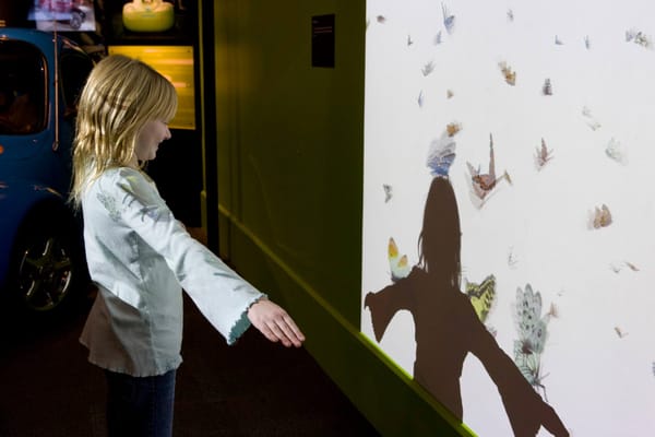 A kid at waves at a projection of butterflies at the Museum of Science & Industry Chicago.